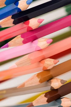Close-up in oblique view over cross stacked crayons in the colors of the color circle with selective sharpness