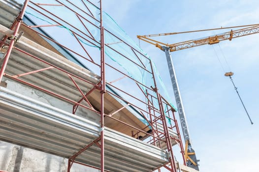 Construction scaffolding of a building under renovation and a crane.