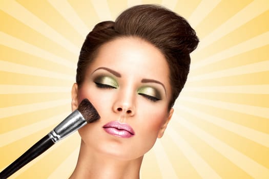 Glamour girl with retro fashion hairstyle applying dry cosmetic tonal foundation on the face using makeup brush on colorful abstract cartoon style background.
