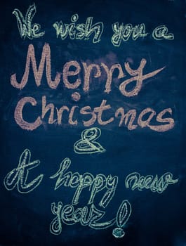 We wish you a Merry Christmas and a happy new year, hand writing with chalk on blackboard, vintage concept