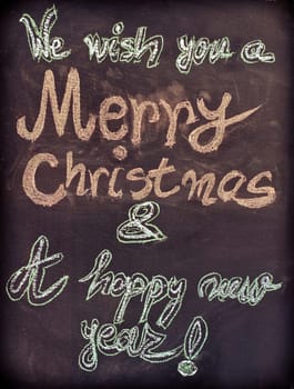 We wish you a Merry Christmas and a happy new year, hand writing with chalk on blackboard, vintage concept