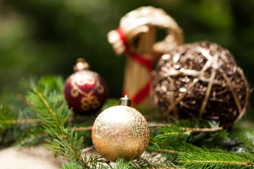 golden Christmas tree balls glittering on tannin branches with snow as macro detail