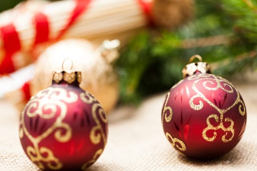 Decoration for Christmas with red and gold Christmas tree balls in front of green fir branches in the background