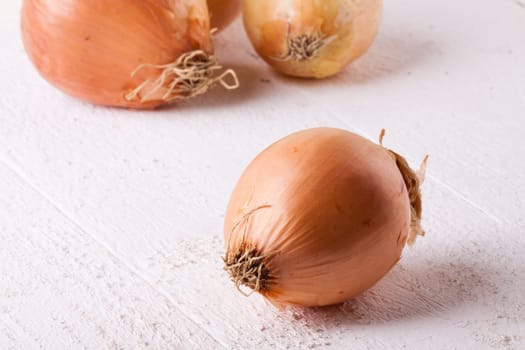 Fresh onions with brown peel on a rustic wooden board as close-up