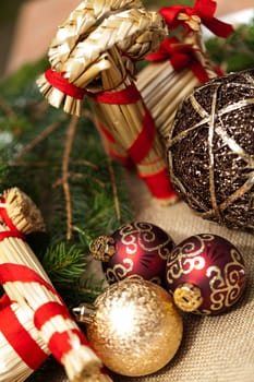 Decoration for Christmas with red and gold Christmas tree balls in front of green fir branches in the background