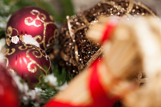 red Christmas baubles between cones and fir branches covered with snow as macro detail