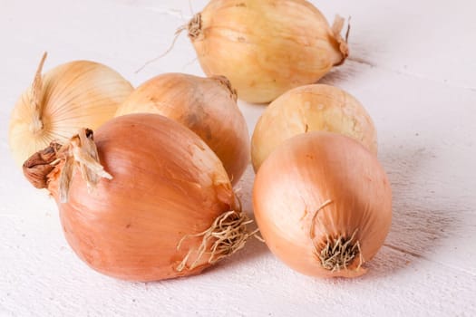 Fresh onions with brown peel on a rustic wooden board as close-up