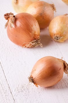 Fresh onions with brown peel on a rustic wooden board as close-up