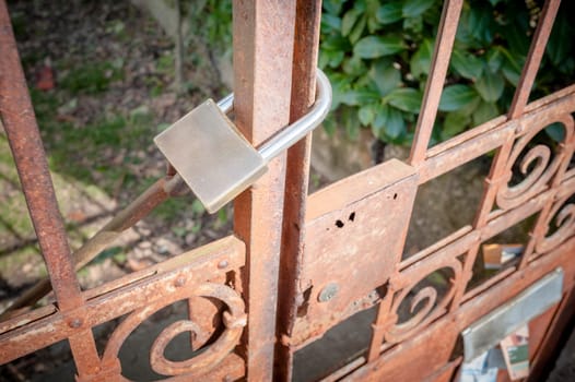 Rusty metal gate closed with padlock - concept image