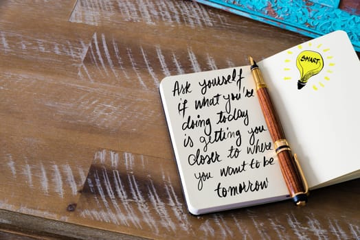 Handwritten text Ask yourself if what you’re doing today is getting you closer to where you want to be tomorrow with fountain pen on notebook. Concept image with copy space available.
