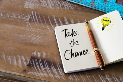 Handwritten text Take The Chance with fountain pen on notebook. Concept image with copy space available.