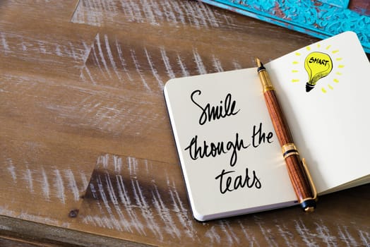Handwritten text Smile Through The Tears with fountain pen on notebook. Concept image with copy space available.