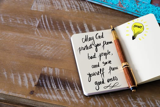 Handwritten text May God protect you from bad people, and save yourself from good ones with fountain pen on notebook. Concept image with copy space available.