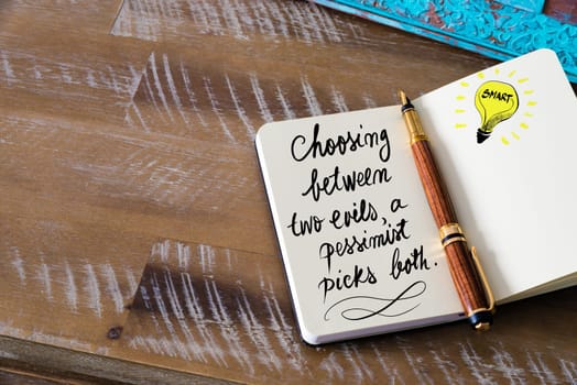 Handwritten text Choosing between two evils, a pessimist picks both with fountain pen on notebook. Concept image with copy space available.