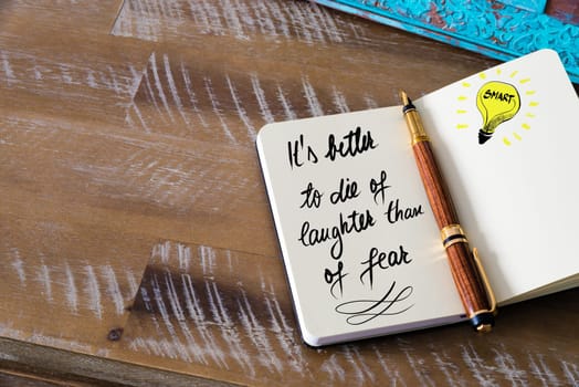 Handwritten text It’s better to die of laughter than of fear with fountain pen on notebook. Concept image with copy space available.