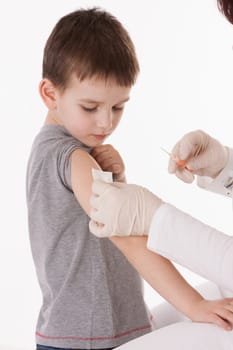 Doctor giving a child injection in arm on isolated image.