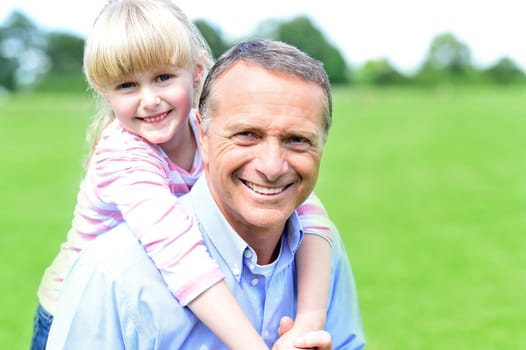 Loving young girl hugging her father from behind