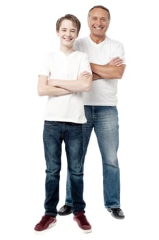 Smiling father and son with arms crossed standing over white.