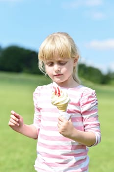 Beautiful little girl eats ice-cream in the summer