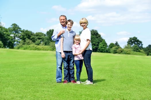 Happy family of four having nice time in summer park