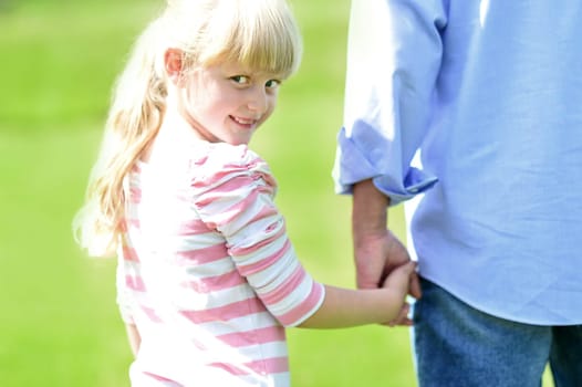Girl holding hands with her father outside