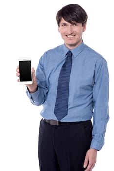 Smiling male executive showing a mobile phone white background.