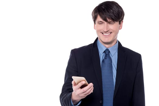Happy businessman is looking his mobile phone and smiling.