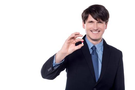 Image of a businessman holding pill in his hand.
