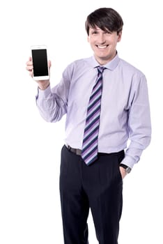 Friendly businessman holding a mobile phone over white.