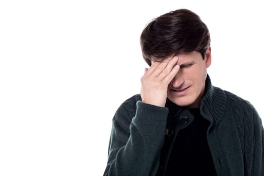 Depressed middle aged man with hand on his forehead.