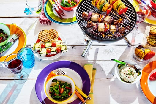 Overhead Well Laid summer table with colorful dish and plates and brazier on white background with vegan bbq skewers