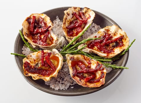 Close Up Still Life View of Plate of Oysters Kilpatrick Prepared with Bacon and Cheese and Served with Salt Garnish on White Background