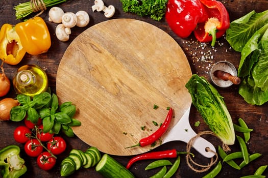 High Angle Still Life View of Cutting Board Surrounded by Fresh Raw Vegetables and Variety of Herbs and Spices on Rustic Wooden Table