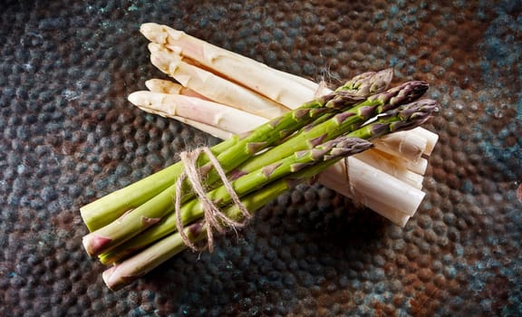 High Angle Still Life View of White and Green Asparagus Stalks Bound Together with Twine and Lying Over Lapped on Textured Rusty Metal Surface