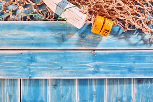Nautical Themed Background with Copy Space - High Angle Still Life of Blue Painted Wood Planks with Natural Rope Fishing Net and Buoy