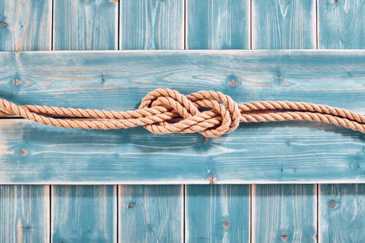 Nautical Themed Background - High Angle Still Life of Double Figure Eight Knot in Natural Rope Across Blue Painted Wood Plank Background with Copy Space