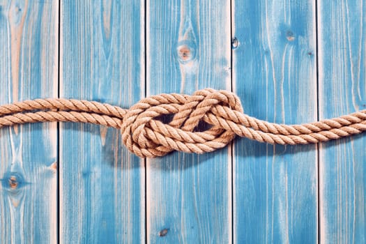 Nautical Themed Background - High Angle Still Life of Double Figure Eight Knot in Natural Rope Across Blue Painted Wood Plank Background with Copy Space