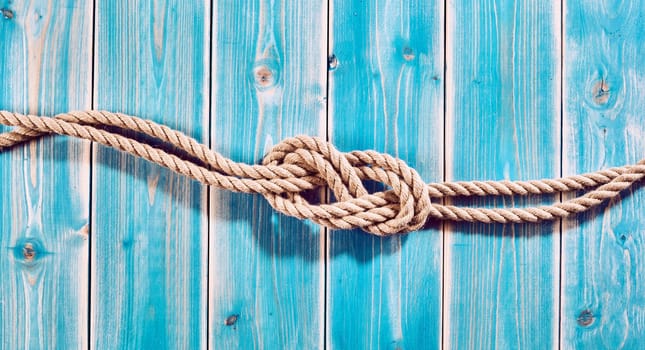 Nautical Themed Background - High Angle Still Life of Double Figure Eight Knot in Natural Rope Across Blue Painted Wood Plank Background with Copy Space