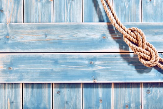 Nautical Themed Background - High Angle Still Life of Double Figure Eight Knot in Natural Rope Across Corner of Blue Painted Wood Plank Background with Copy Space