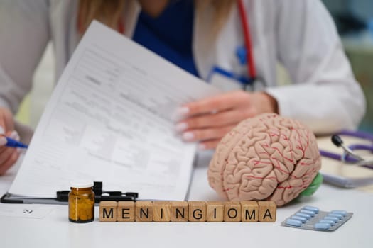 A physician carefully studies a detailed patient file, focusing on meningioma while surrounded by various medical tools
