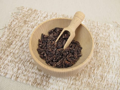 Cocoa nibs from raw cocoa in a wooden bowl