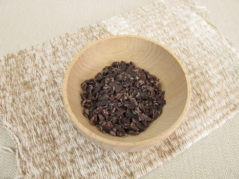 Cocoa nibs from raw cocoa in a wooden bowl