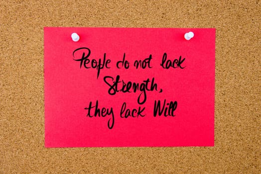 Red paper note with handwritten text People Do Not Lack Strength, They Lack Will pinned on cork board with white thumbtacks