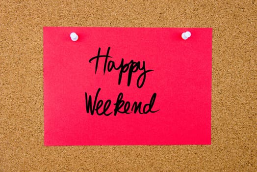 Red paper note with handwritten text Happy Weekend pinned on cork board with white thumbtacks