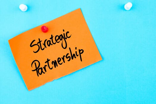 Strategic Partnership written on orange paper note pinned on cork board with white thumbtack, copy space available