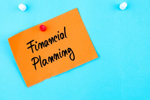 Financial Planning written on orange paper note pinned on cork board with white thumbtack, copy space available