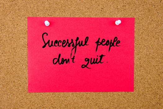 Red paper note with handwritten text Successful People Do Not Quit pinned on cork board with white thumbtacks