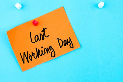 Last Working Day written on orange paper note pinned on cork board with white thumbtack, copy space available