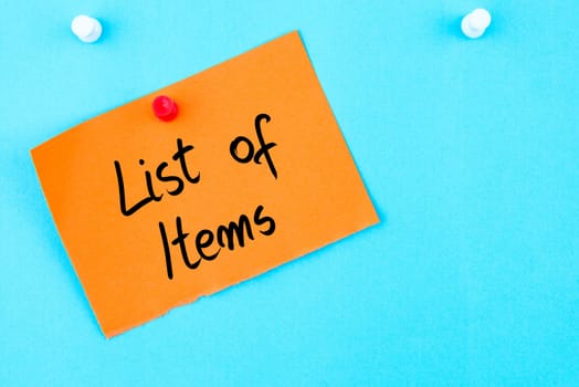 List Of Items written on orange paper note pinned on cork board with white thumbtack, copy space available