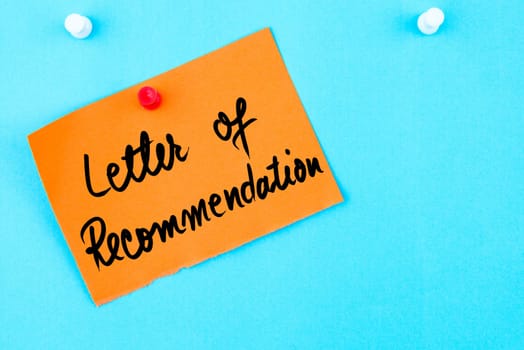 Letter Of Recommendation written on orange paper note pinned on cork board with white thumbtack, copy space available